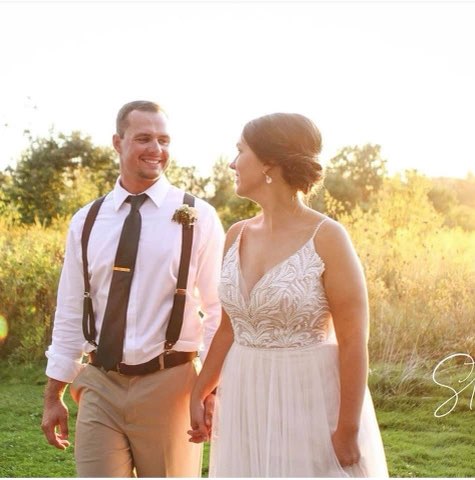 A Joyful Couple Walks Hand In Hand Through A Sunlit Field, Dressed Elegantly For Their Wedding. They Share Smiles, Reflecting Happiness And Love.